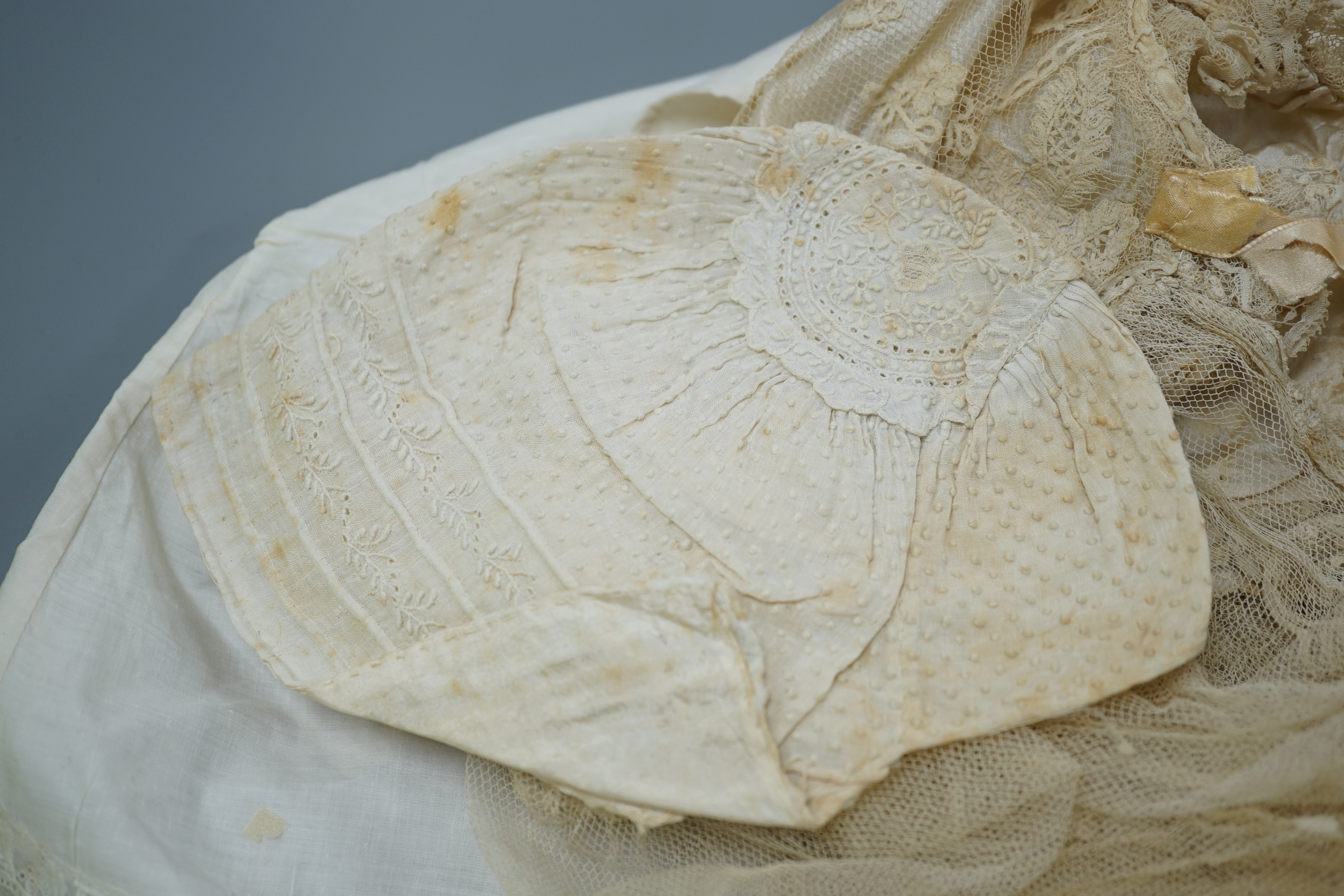 A collection of 19th century babywear, lace and cutwork bonnets and a christening bonnet and veil